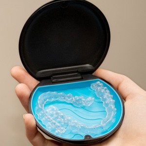 Patient holding clear aligners in black and blue case