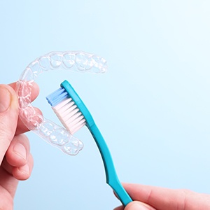 Person using toothbrush to clean a clear aligner