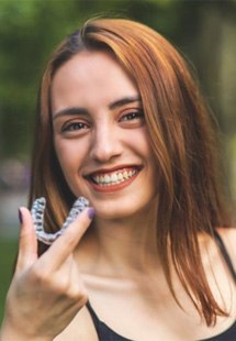 a woman near Westfield holding her Invisalign aligners
