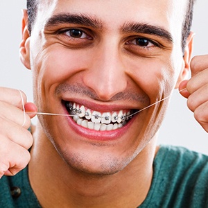 Closeup of smiling man with braces in Enfield flossing 