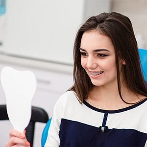 Woman looking at smile in mirror after orthognathic surgery