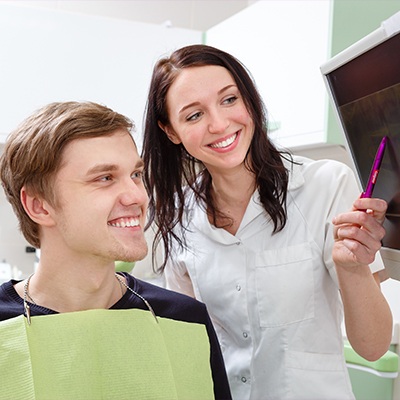 Orthodontic team member and patient looking at digital smile design on chairside computer screen