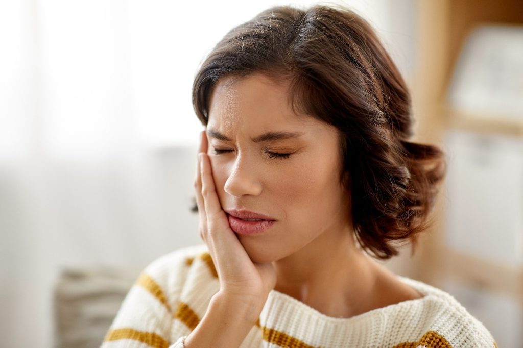 Woman experiencing oral sores because of braces.