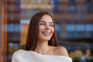 Woman in white sweater with braces smiling