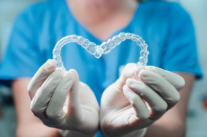 Dentist with gloves carefully holding two Invisalign trays